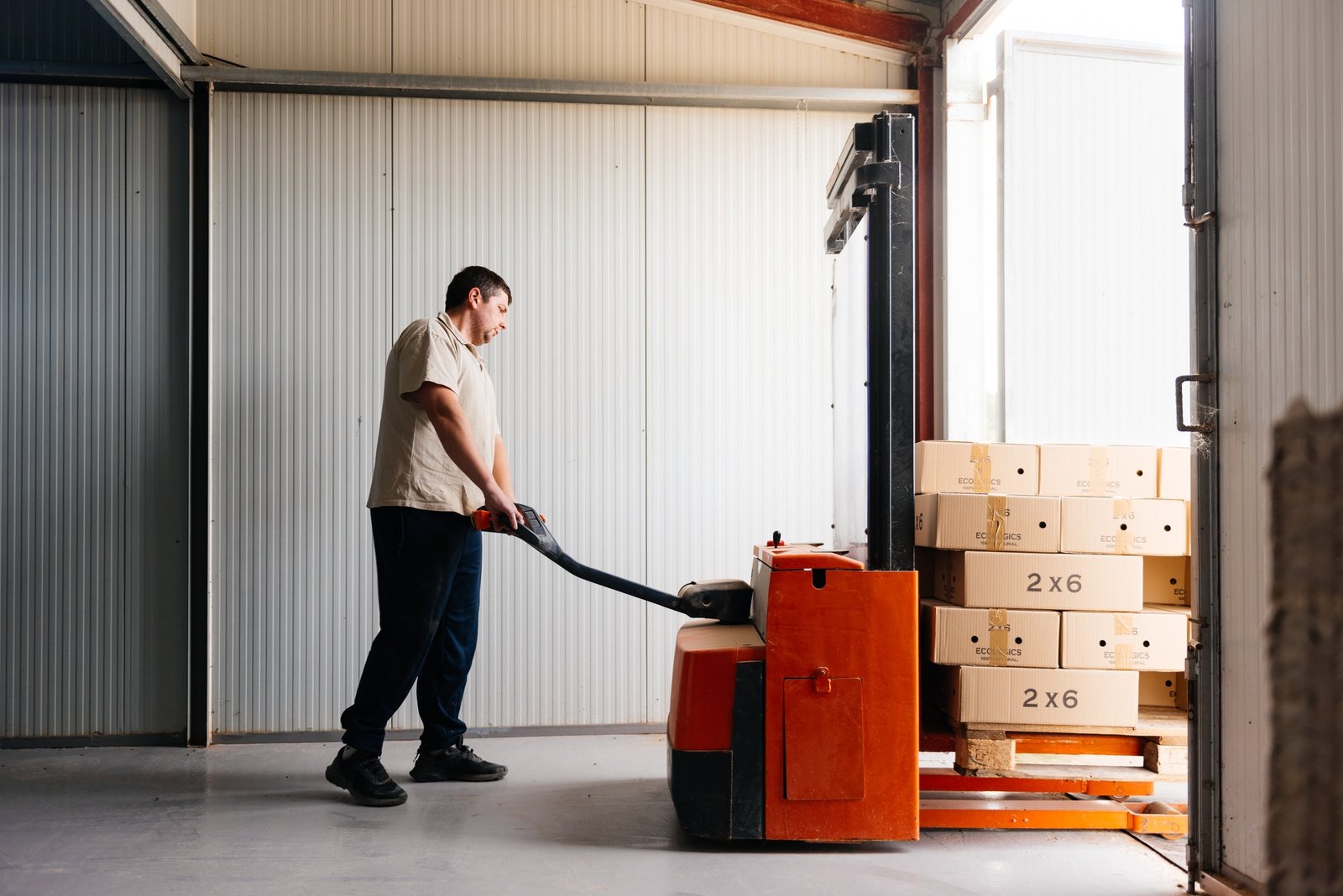 Man transporting boxes with forklift in a farm facility